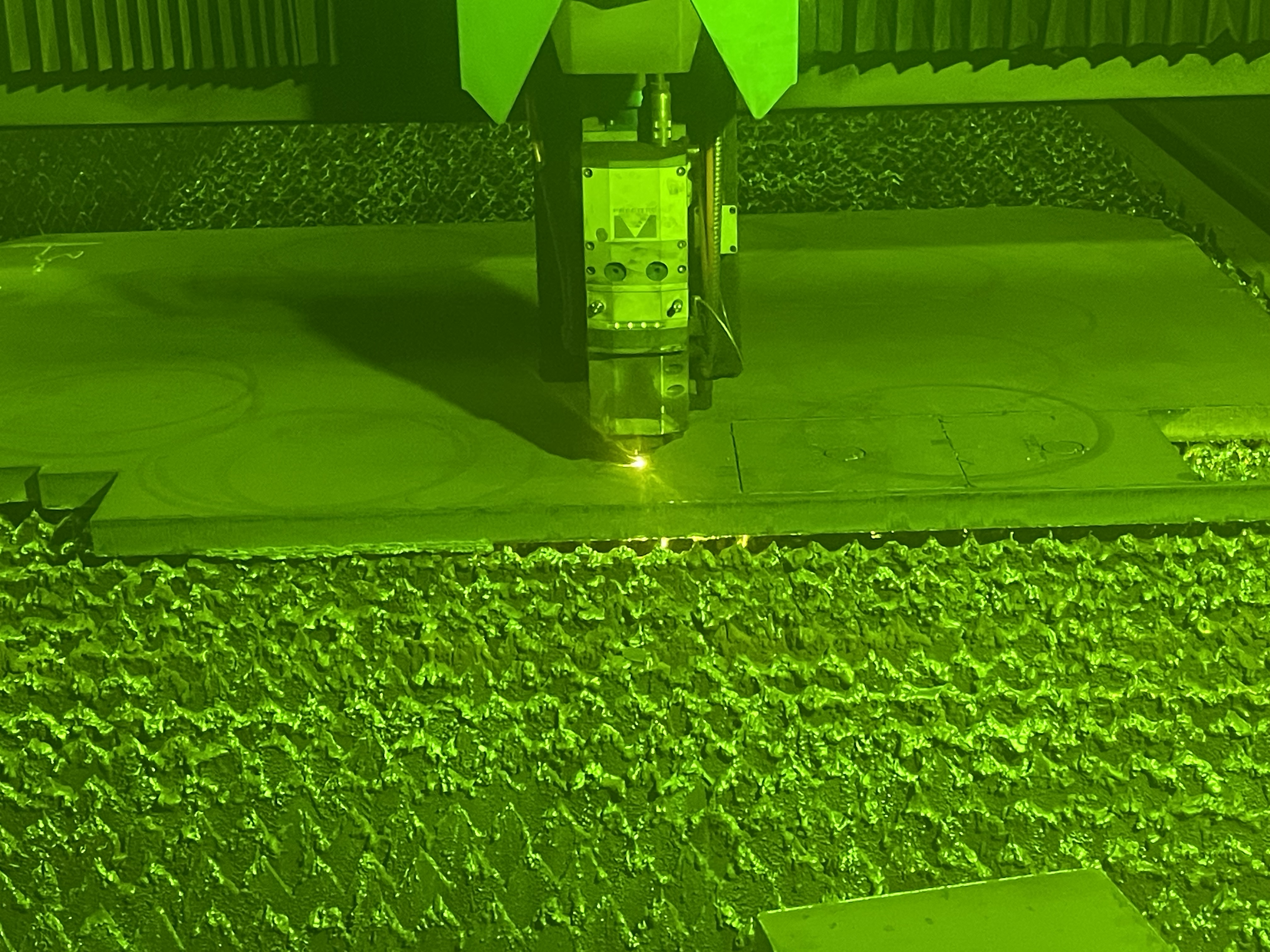 Tête laser découpant une tôle dans la machine